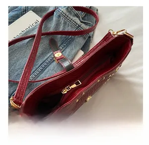 Détail de la fermeture dorée et poche intérieure du sac croissant bordeaux en crocodile