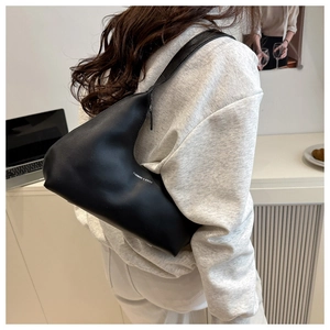 Close-up of asymmetrical black shoulder bag with Fashion & Bags print on model