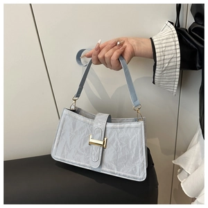 Close-up of light blue pleated faux leather baguette bag with a golden metal buckle