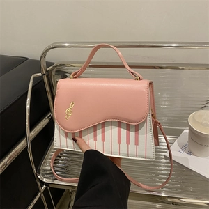 Pink and white piano note crossbody bag on a modern stainless steel shelf display