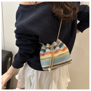 Detail of colorful woven bucket bag with gold chain strap and pearl drawstring tassels