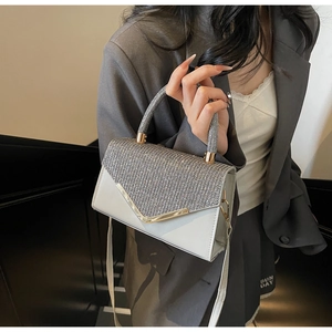 Detailed view of silver rhinestone handbag with gold V-clasp and elegant chain strap