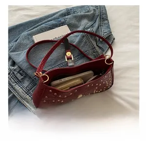 Détail du sac croissant bordeaux à motif crocodile avec rivets montrant sa grande capacité