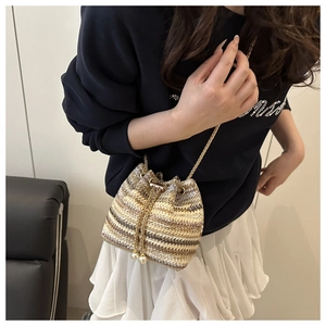 Detail of woven bucket bag featuring pearl drawstrings and elegant metal chain strap