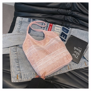 Gros plan d'un cabas en dentelle rose avec broderie florale sur une veste en jean