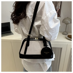 Detail of the canvas and black leather stitching on a tote bag with gold zipper