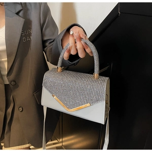 Detail of silver rhinestone evening bag with sparkling curved handle and V-shaped metal trim