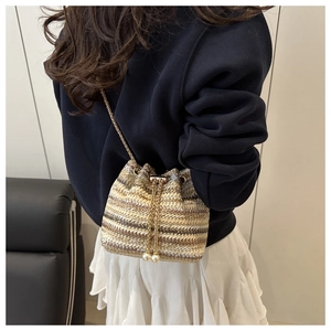 Detailed shot of woven bucket bag with gold chain and pearl drawstring accents