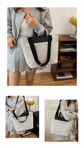 Detail of a large canvas tote bag with contrast black handles in a cozy home setting
