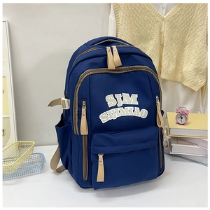 Close-up of navy canvas backpack with SJM logo print and khaki zipper accents