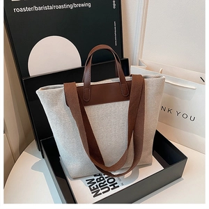 Detail of a minimalist canvas tote bag with contrast brown straps in gift packaging