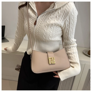 Close-up of beige leather handbag with gold geometric metal clasp worn by model