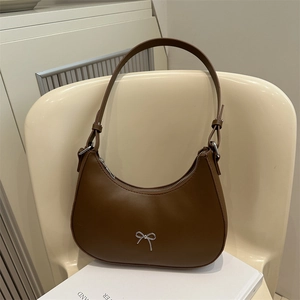 Detail of hobo bag in brown PU leather featuring a stylish silver metal bow decoration