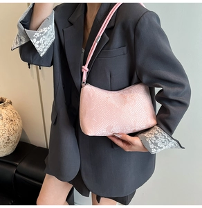 Detail of pink faux snakeskin shoulder bag with textured pattern shown on a model