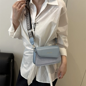 Minimalist light blue crossbody bag with woven detail and geometric wide strap on model