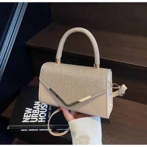 Close-up of beige crossbody bag with shimmering rhinestone lid and gold hardware accents