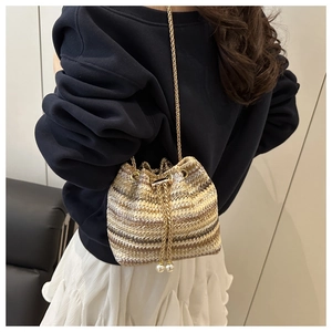 Detailed knit texture of striped bucket bag with pearl drawstring and gold chain strap