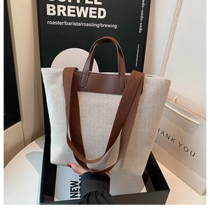 Detail of linen tote bag with brown leather handles and adjustable fabric shoulder strap