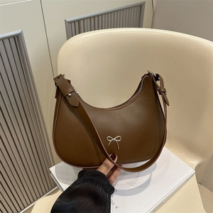Detail of dark brown faux leather hobo bag featuring a silver bow metal decoration