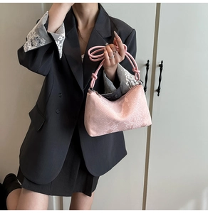 Detail of pink snake-embossed leather texture and knotted strap on minimalist shoulder bag
