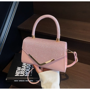Detail of pink crossbody bag with rhinestone lid and gold V-shaped metal buckle