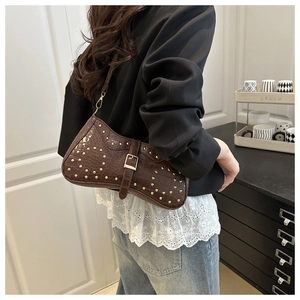 Détail du sac croissant marron à motif crocodile avec rivets dorés et finitions métalliques