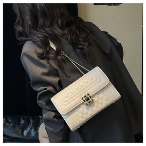 Quilted off-white chain bag with gold hardware worn by model over a dark blazer