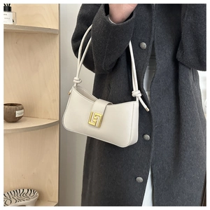 Detail of white leather crescent bag featuring gold geometric buckle and knotted strap
