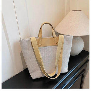 Detailed close-up of a canvas tote bag featuring brown leather handles on a black cabinet