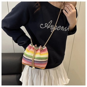 Detail of colorful woven bucket bag with rainbow stripes, gold chain, and pearl charms