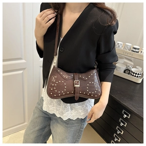 Détail du sac marron foncé texture crocodile avec clous dorés et sangle à boucle