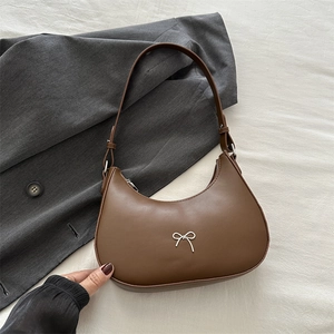 Detailed top view of a brown leather crescent hobo bag with silver bow logo on fabric