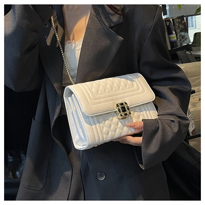 Detail of white quilted leather crossbody bag with black gemstone buckle and gold chain