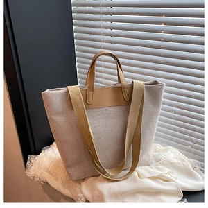 Detail of grey canvas tote bag with brown leather handles and adjustable shoulder strap