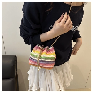 Detail view of colorful striped knit bucket bag with gold chain strap and pearl decor