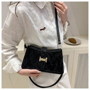 Detail of elegant black baguette bag featuring a metallic gold H-shaped buckle closure