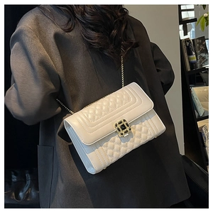 Close-up of white quilted crossbody bag with gold chain strap and metal buckle
