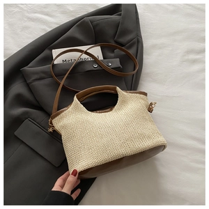 Détail du sac cabas en paille tissée avec bordure en cuir marron sur blazer gris