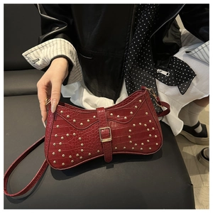 Détail du sac croissant bordeaux à motif crocodile avec rivets dorés et boucle métal