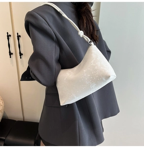 Detail of white textured faux snake leather shoulder bag with decorative strap knot