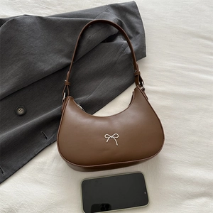 Brown half-moon hobo bag with silver bow detail and smartphone for size reference