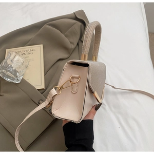 Detail of beige leather bag with shimmering rhinestones and gold V-shaped hardware