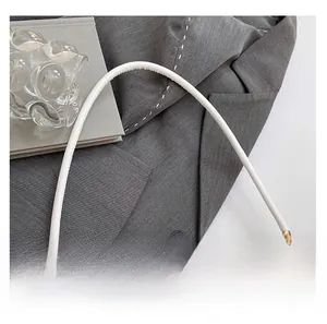 Detail of grey leather handbag showing cylindrical handle and matte gold metal hardware