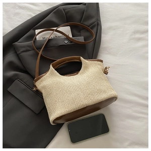 Détail d'un sac cabas en paille tissée avec garniture en cuir brun et base ovale solide