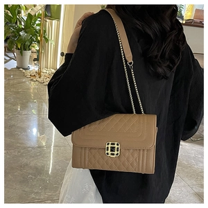 Close-up of brown quilted crossbody bag with gold chain strap and metal lock detail