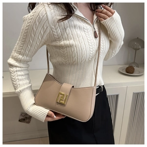 Detail of apricot shoulder bag with golden buckle on a model in knit cardigan