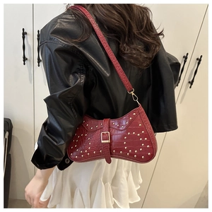 Détail du sac croissant rouge avec motif crocodile et rivets dorés décoratifs
