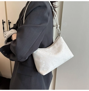 Detail of white reptile texture shoulder bag with knot strap and silver zipper closure