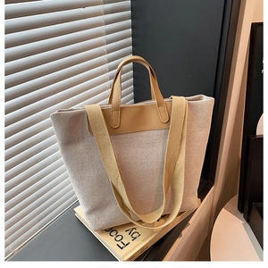 Detail of canvas tote bag with brown leather handles and adjustable shoulder strap