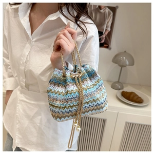 Detail of woven bucket bag with zigzag pattern, gold chain handle and pearl drawstrings